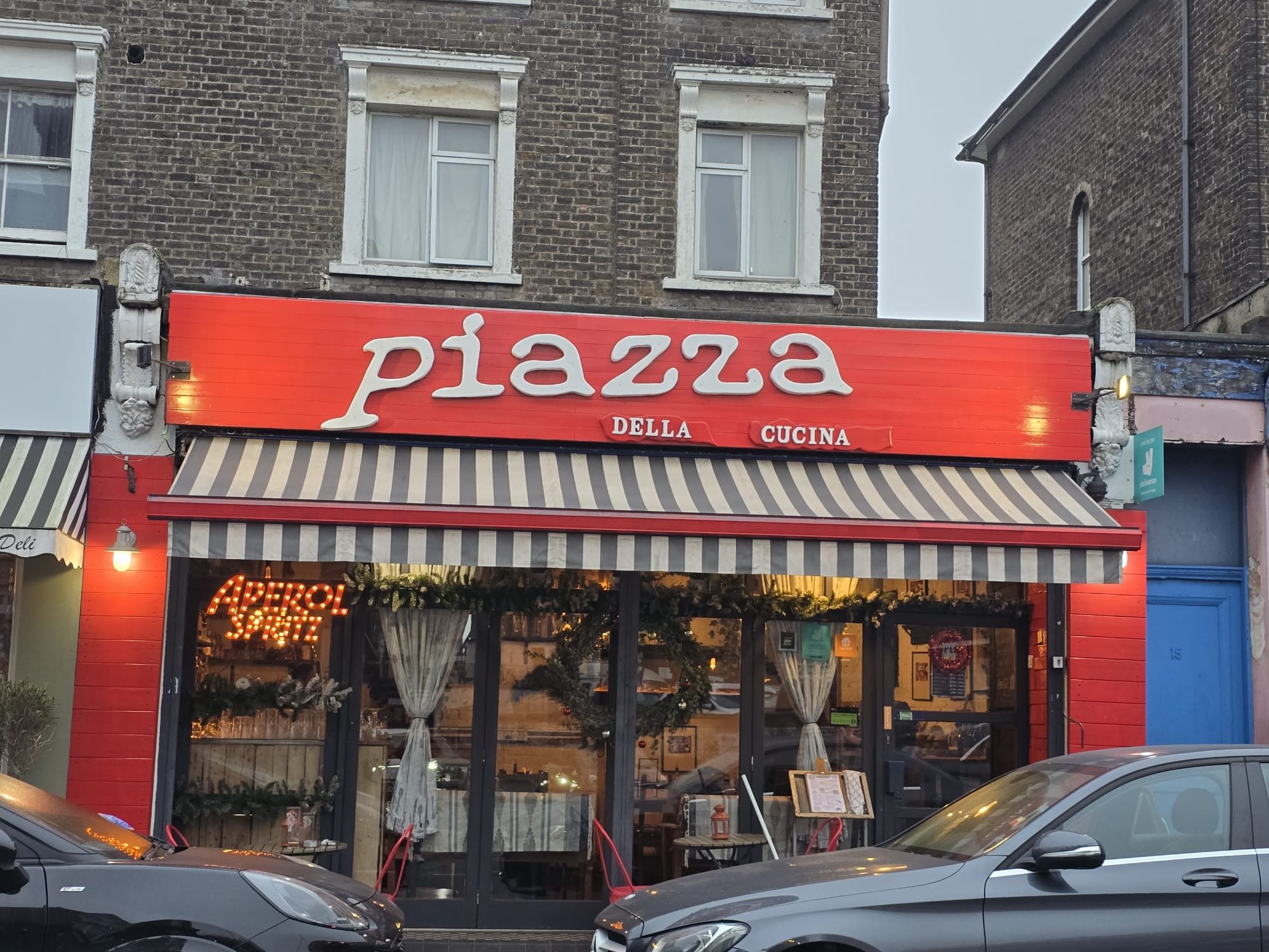 Exterior of Piazza Della Cucina with large windows and a red and white striped awning.